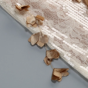 Vue détaillée des paillettes dorées et des appliques de feuilles 3D sur tissu en maille