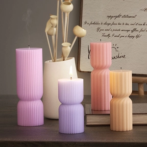 Detailed view of four ribbed pillar candles in pink, purple, and beige for home decor