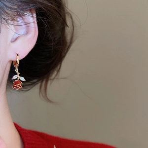 Detail view of red rose earrings with gold leaves on model for elegant styling