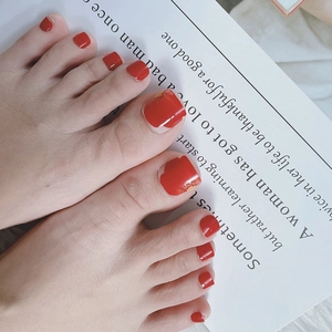 Close-up of red and gold foil press-on toenails on an open book background