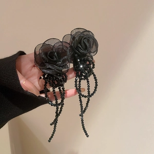 Détail d'une pince à cheveux rose en organza noir avec glands en perles de style vintage