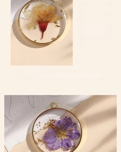 Close-up of handmade resin pendant with dried flowers and gold foil in copper frame