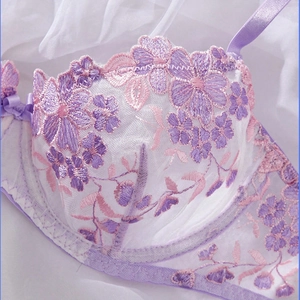 Detail view of semi-transparent light purple lace bra with pink floral embroidery and bow