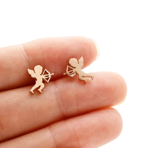 Cute gold Cupid angel stud earrings in matte metal finish held on a finger for size