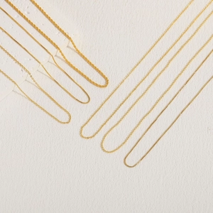 Minimalist 18K gold plated copper necklaces in various chain styles on a white textured background