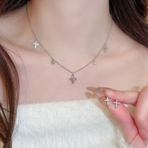 Detail of silver cross necklace and earrings set with shimmering zircon stones on model