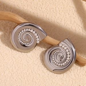 Detailed macro view of conch shaped stud earring with faux pearl on wooden stand