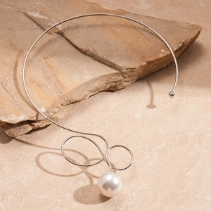 Detail view of a silver geometric choker with an infinity twist and white pearl accent
