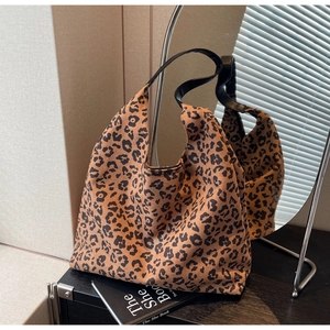 Macro shot of large leopard print tote bag with black leather strap in mirror reflection