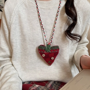 Close-up of a handmade red and green knit heart pendant with wooden buttons and tassels