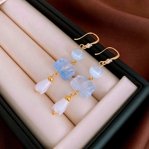 Detail view of gold-plated lotus earrings with blue glass flowers on jewelry box