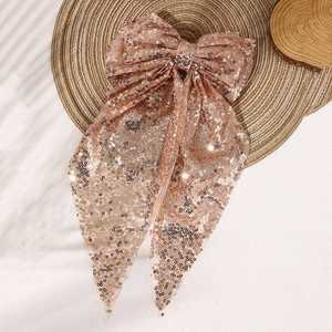 Detail of rose gold sequin oversized bow hair clip with elegant long trailing streamers