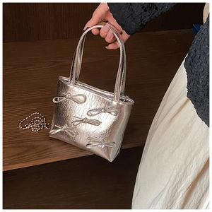 Detailed shot of silver metallic handbag with bow accents and bead chain strap