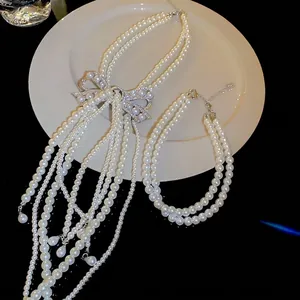 Collier de perles multicouche élégant avec pendentif nœud en strass et pompons fins