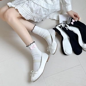 Detail of JK style frilly socks with pink bows and black lace trimming on soft white cotton