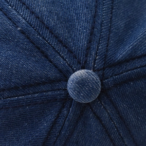 Détails macro du bouton supérieur et des coutures à six pans de la casquette en denim