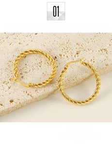 Detailed macro view of gold-plated titanium steel hoop earrings with twisted texture design