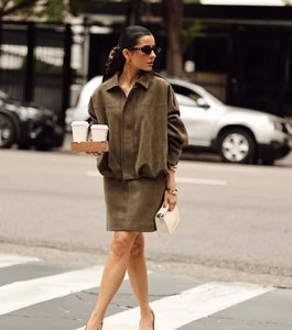 Street style view of olive green suede jacket and mini skirt set worn by a model in the city