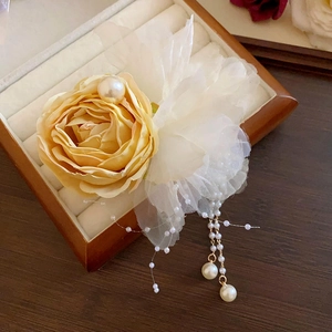Detail of elegant champagne silk rose and white lace floral clip with pearl tassels
