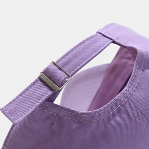 Detail of purple baseball cap showing adjustable metal buckle and premium cotton stitching