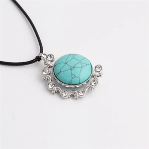 Macro detail of turquoise hamsa pendant with sparkling rhinestones and silver metal finish