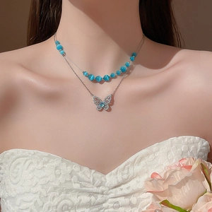 Double-layered silver necklace with blue cat-eye beads and zircon butterfly pendant detail
