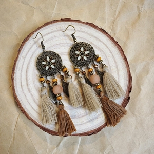 Close-up of Bohemian earrings with bronze leaf charms, wood beads and cotton tassels