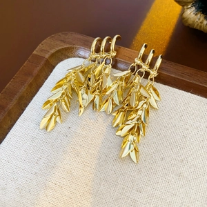 Macro detail of golden wheat ear tassel earrings on a linen jewelry display tray