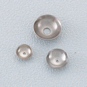 Flat lay of three silver stainless steel saucer spacer beads on a textured blue surface