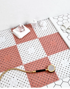 Close-up of pink and white interlocking TPE bathroom mats with non-slip texture
