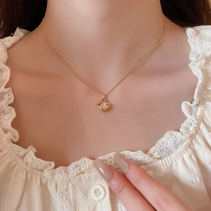 Detail of 18k gold plated necklace with a hollow square pendant and cubic zirconia stone