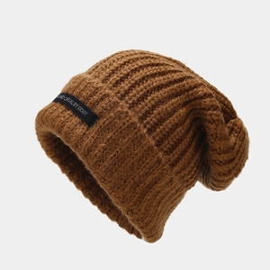 Detalle del gorro de punto marrón mostrando la textura de canalé y la etiqueta tejida