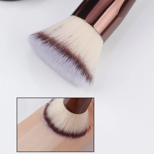 Dual-ended foundation brush with dense bristles showing makeup application on skin