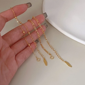 Detail of four different gold S925 sterling silver beaded and Figaro chain bracelets