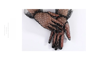 Close-up of black polka dot sheer mesh lace gloves with delicate ruffled wrist detail
