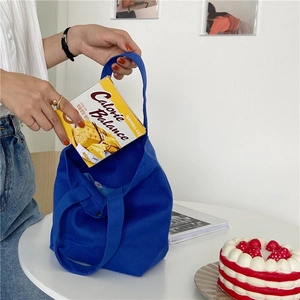 Close-up of a blue canvas tote bag being used as a lunch bag in a minimalist setting