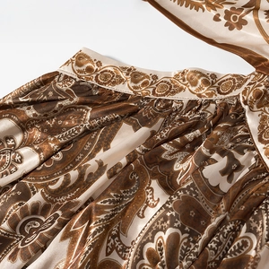 Dettaglio del taglio in vita su un abito satinato con motivo paisley e stile boho