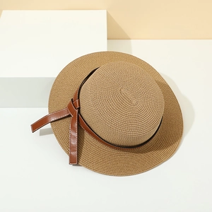 Summer wide brim straw hat with brown leather belt and bow on a geometric block