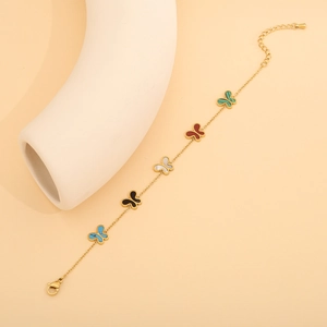 Détail du collier papillon doré avec breloques colorées bleu, noir, blanc, rouge et vert