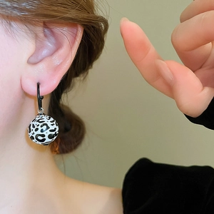 Gros plan de boucles d'oreilles rondes à motif léopard noir et blanc au style rétro