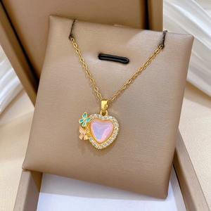 Detail of gold necklace with pink heart pendant and colorful crystal butterfly charms