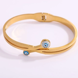 Detail of gold evil eye cuff bracelet with sparkling rhinestones on white background