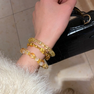 Detailed view of layered citrine beaded bracelets and gold woven chain on wrist