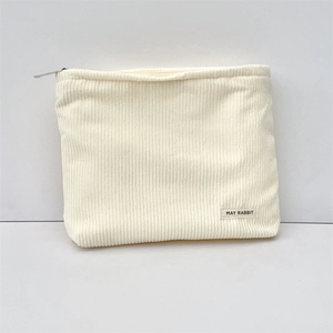 Close-up of cream corduroy cosmetic bag showing fine texture and zipper detail