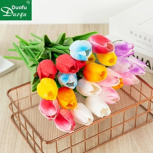 Vibrant multi-color artificial tulips in a rose gold metal basket on wooden table