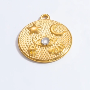 Macro shot of gold stainless steel celestial charm with moon, star, and eye engraving