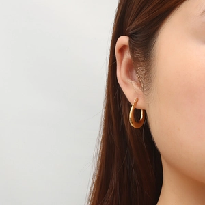 Minimalist 18K gold plated stainless steel oval hoop earrings worn by a female model