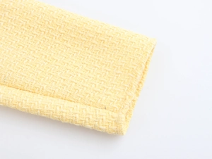 Close-up of pale yellow tweed fabric texture with intricate woven pattern details