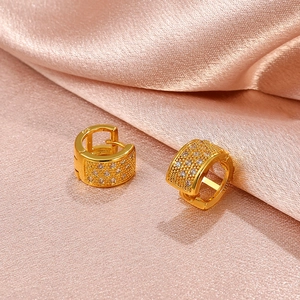 Elegant gold geometric earrings with white zircon crystals on soft pink silk background