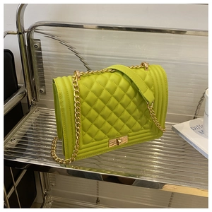 Detail of green quilted crossbody bag showing gold chain strap and metal turn-lock